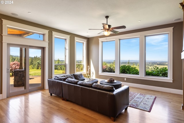 living room featuring ceiling fan, plenty of natural light, and light wood-type flooring