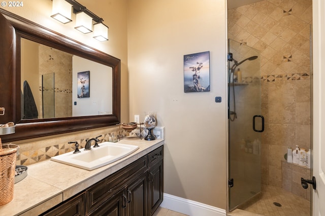 bathroom featuring vanity, a shower with shower door, and backsplash