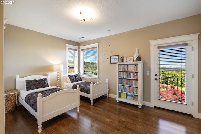 bedroom featuring dark hardwood / wood-style floors, access to exterior, a textured ceiling, and multiple windows