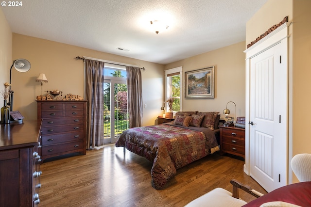 bedroom featuring a textured ceiling, access to outside, and dark hardwood / wood-style floors