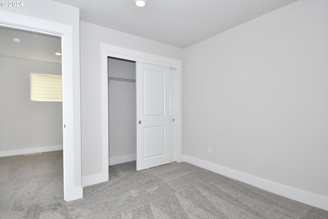 unfurnished bedroom featuring light colored carpet and a closet