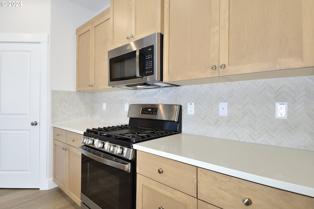 kitchen featuring decorative backsplash, light wood-type flooring, stainless steel appliances, and light brown cabinetry