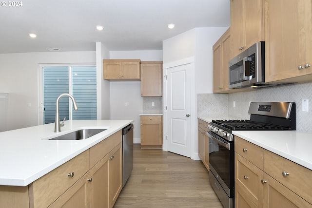 kitchen with decorative backsplash, light hardwood / wood-style floors, sink, and appliances with stainless steel finishes