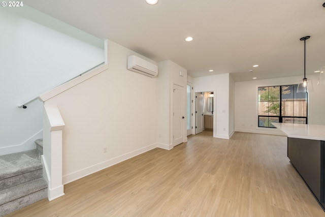 unfurnished living room with a wall mounted air conditioner and light hardwood / wood-style floors