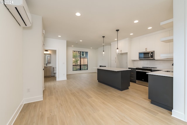 kitchen with a wall mounted air conditioner, stainless steel appliances, a center island, pendant lighting, and white cabinetry