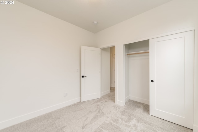 unfurnished bedroom with light colored carpet and a closet