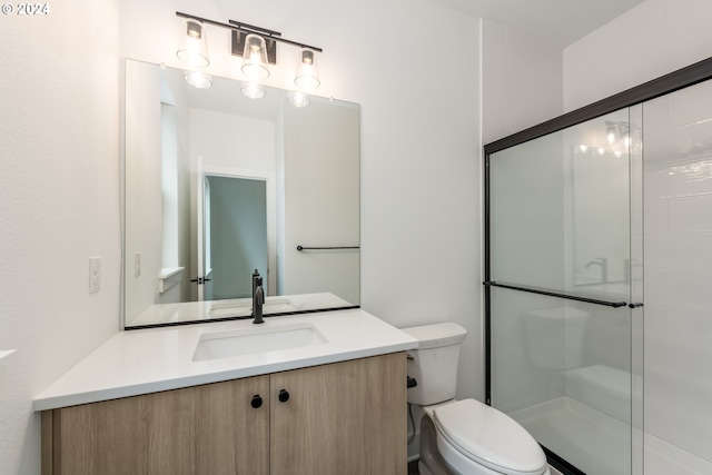 bathroom featuring vanity, a shower with shower door, and toilet