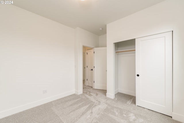 unfurnished bedroom featuring a closet and light carpet