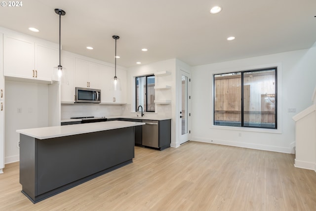 kitchen with stainless steel appliances, light hardwood / wood-style flooring, a kitchen island, and white cabinets