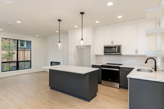 kitchen with sink, stainless steel appliances, a center island, and white cabinets