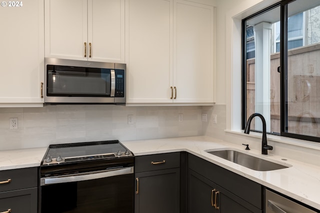 kitchen with sink, appliances with stainless steel finishes, light stone counters, and white cabinets