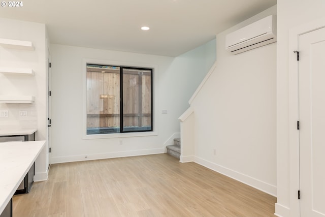 unfurnished living room featuring a wall mounted AC and light hardwood / wood-style flooring