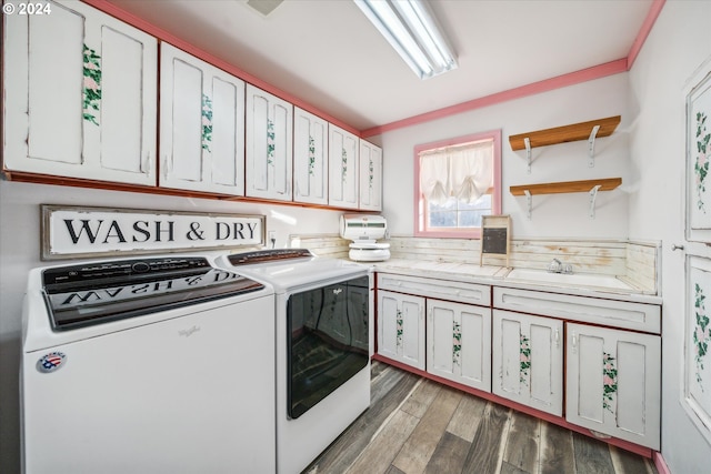 washroom with cabinets, ornamental molding, dark wood-type flooring, and washing machine and clothes dryer