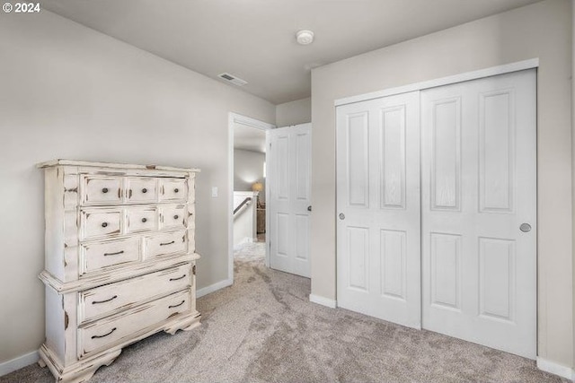 unfurnished bedroom with light carpet and a closet