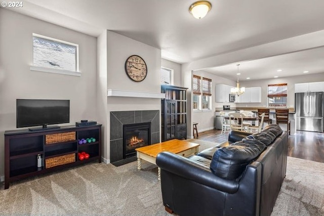 living room featuring a fireplace, wood-type flooring, and an inviting chandelier