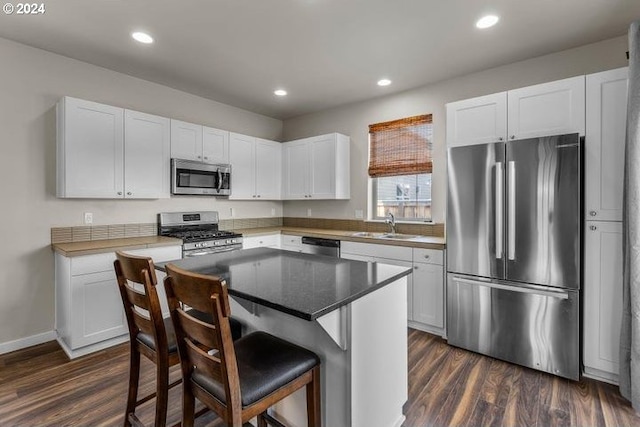 kitchen featuring a breakfast bar, a center island, dark hardwood / wood-style flooring, white cabinetry, and stainless steel appliances