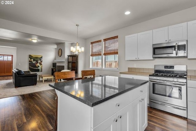 kitchen with a center island, white cabinets, dark wood-type flooring, and appliances with stainless steel finishes