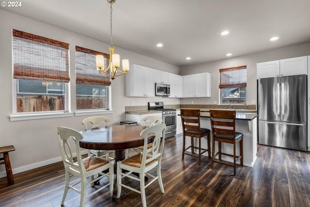 dining space with sink, dark hardwood / wood-style flooring, and a notable chandelier