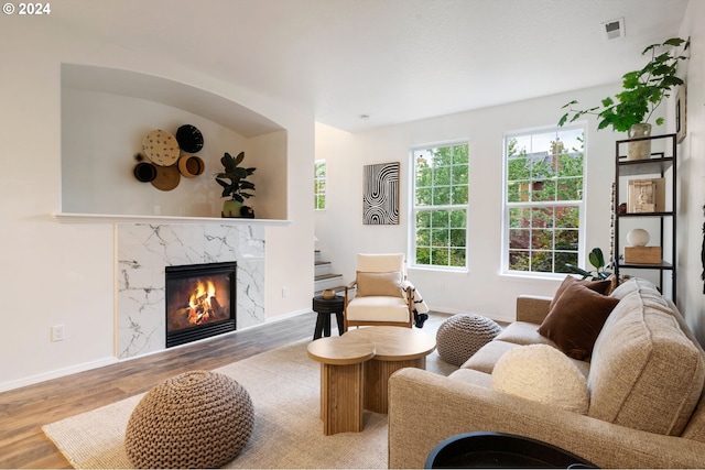 living room with a high end fireplace and light hardwood / wood-style flooring