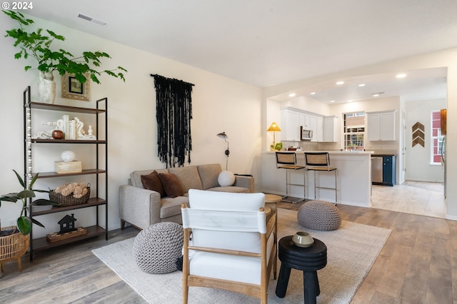 living area with visible vents, recessed lighting, and light wood-style floors