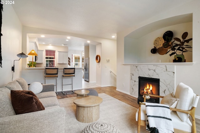 living room featuring recessed lighting, a fireplace, light wood-type flooring, and baseboards
