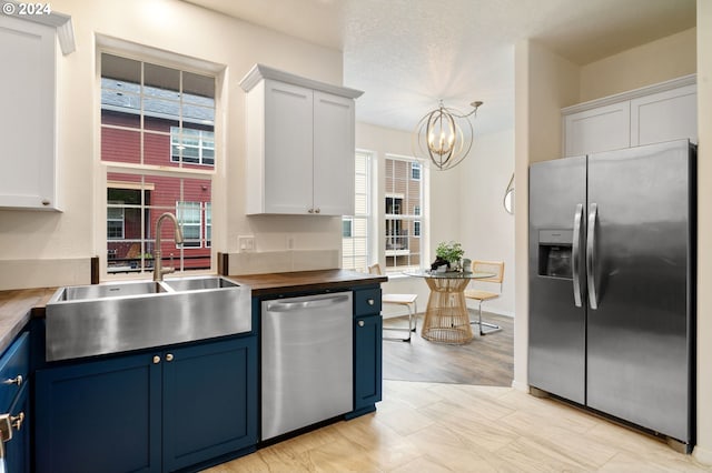 kitchen with blue cabinetry, appliances with stainless steel finishes, a chandelier, and a sink
