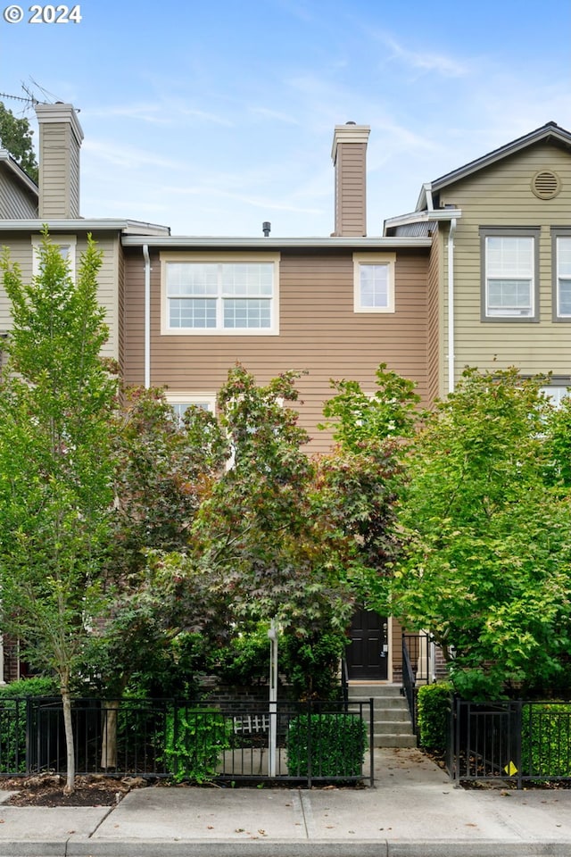 townhome / multi-family property featuring a fenced front yard and a chimney