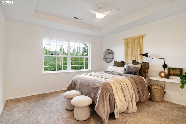 bedroom with a tray ceiling, ceiling fan, and carpet flooring