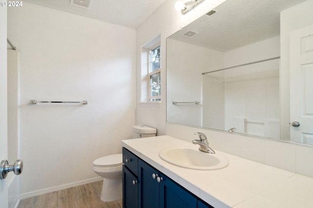 bathroom featuring walk in shower, vanity, toilet, and hardwood / wood-style floors