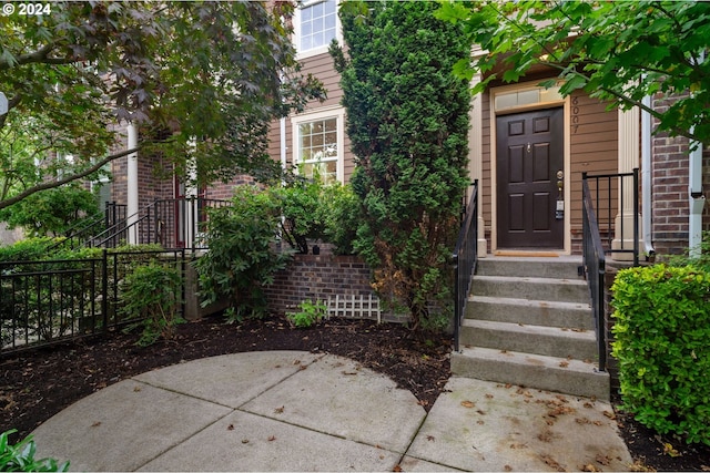 entrance to property featuring a patio, fence, and brick siding