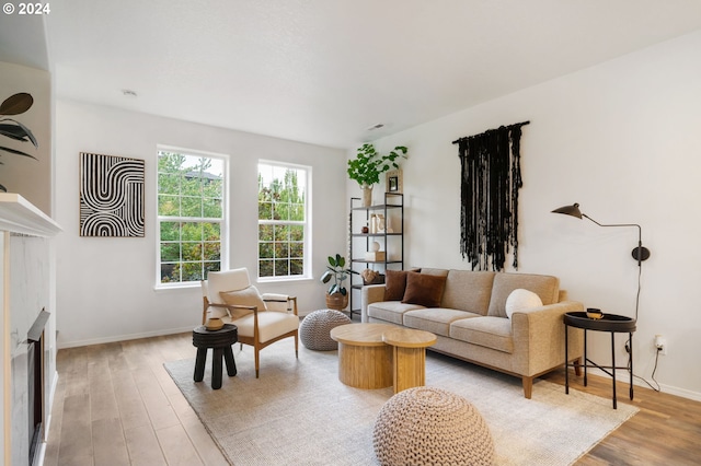 living room with a glass covered fireplace, visible vents, baseboards, and light wood-style flooring
