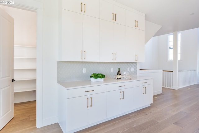 kitchen with white cabinets, backsplash, and light hardwood / wood-style flooring