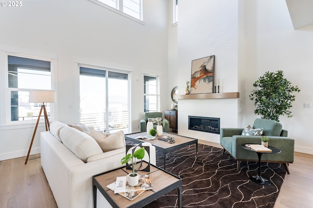 living room featuring a towering ceiling, a large fireplace, and light hardwood / wood-style flooring