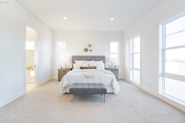 bedroom featuring light carpet and ensuite bath