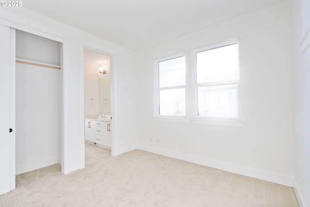 unfurnished bedroom featuring connected bathroom, sink, and light carpet