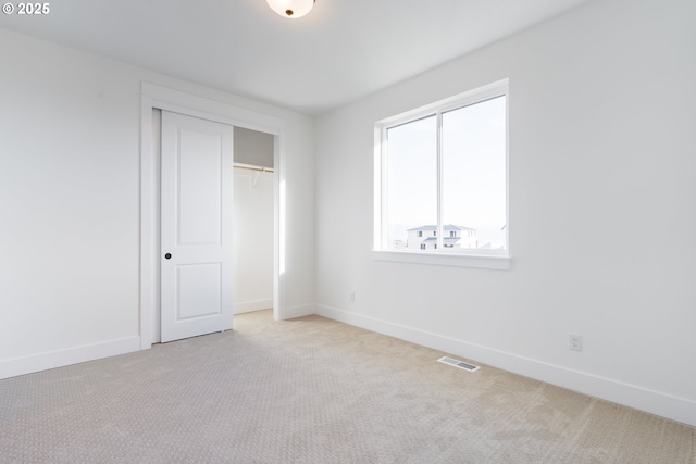 unfurnished bedroom featuring light colored carpet and a closet