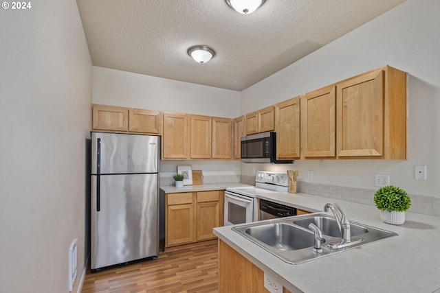 kitchen with light brown cabinetry, sink, a textured ceiling, appliances with stainless steel finishes, and light hardwood / wood-style floors