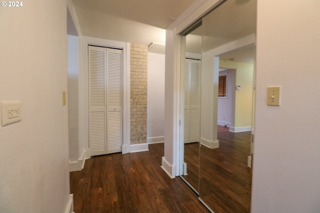 hall with dark wood-type flooring and brick wall