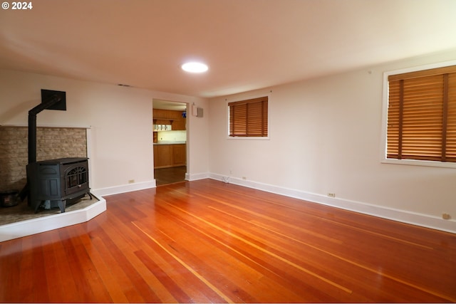 unfurnished living room with wood-type flooring and a wood stove