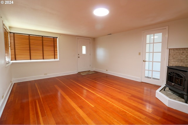 unfurnished living room featuring hardwood / wood-style floors and a wood stove