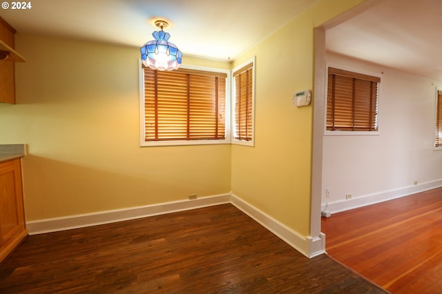 unfurnished dining area with dark wood-type flooring