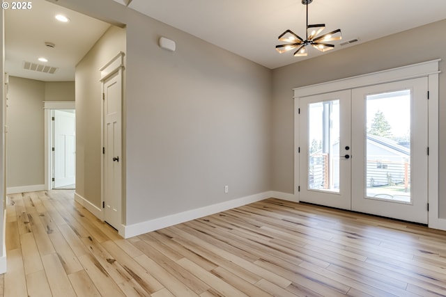 entryway with a notable chandelier, french doors, and light hardwood / wood-style floors