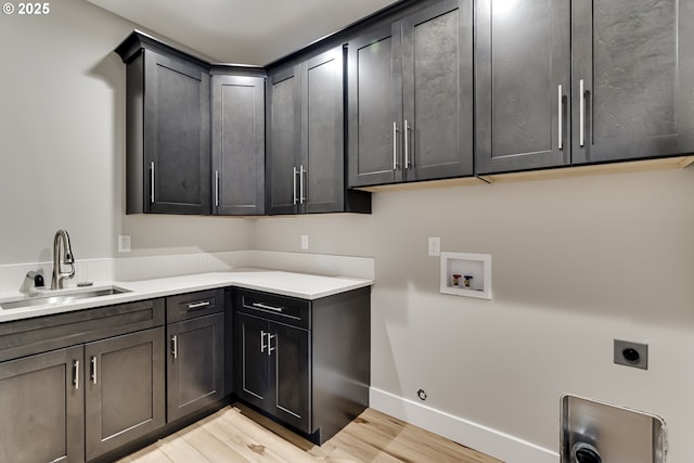 clothes washing area with cabinets, sink, washer hookup, hookup for an electric dryer, and light wood-type flooring