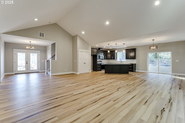 unfurnished living room with light hardwood / wood-style flooring, a chandelier, and a healthy amount of sunlight