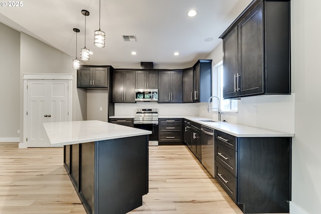 kitchen featuring a center island, sink, light hardwood / wood-style flooring, pendant lighting, and stainless steel appliances