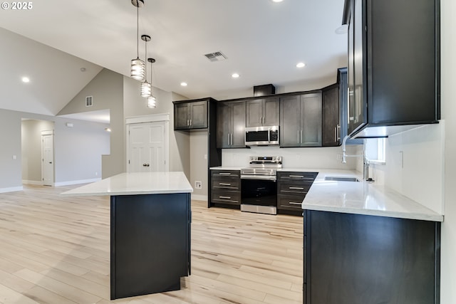 kitchen with light stone countertops, a center island, stainless steel appliances, sink, and hanging light fixtures