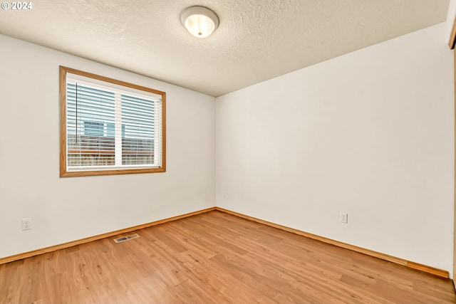 spare room featuring hardwood / wood-style floors and a textured ceiling