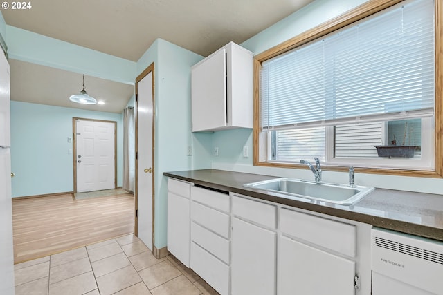 kitchen featuring sink, pendant lighting, dishwashing machine, white cabinets, and light wood-type flooring