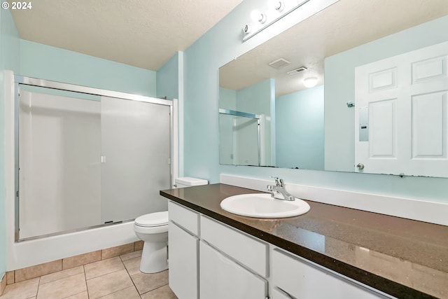 bathroom with a textured ceiling, vanity, tile patterned floors, and a shower with shower door