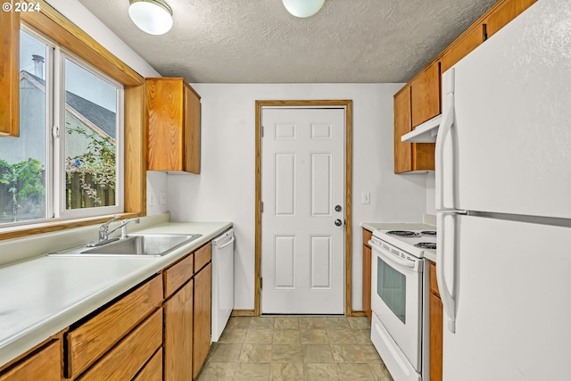 kitchen with a textured ceiling, white appliances, and sink